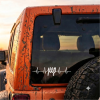 Mud-splattered orange Jeep rear corner with a mounted spare tire and a heartbeat-style Jeep logo on the rear window