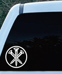 Close-up of a car window with a white circular sticker showing two crossed nails inside a circle (bottom-left).