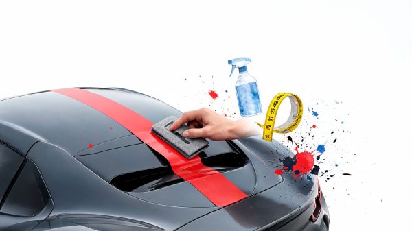 Car being polished for detailing: hand with polishing pad on hood with red stripe, spray bottle and tape measure in the background.